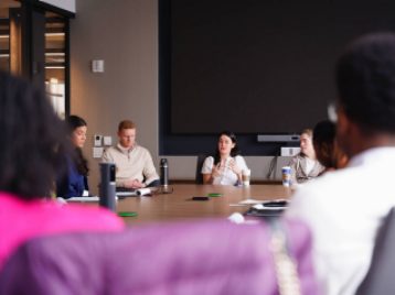 Madison Square Garden employees sitting at a large conference table, answering UM student questions.